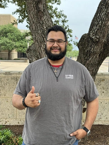 Photo of David in front of a tree in a 12th Man Technology shit with a thumbs up.