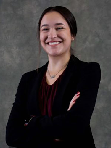 Photo of Elise with arms crossed wearing a black suit.