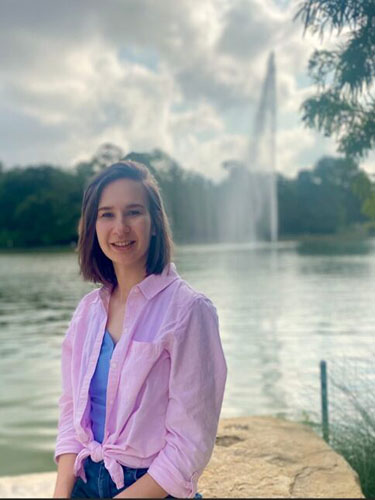 Photo of Sierra by a pond with a fountain in the background.