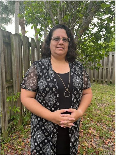 Photo of Angela in a yard by a tree.